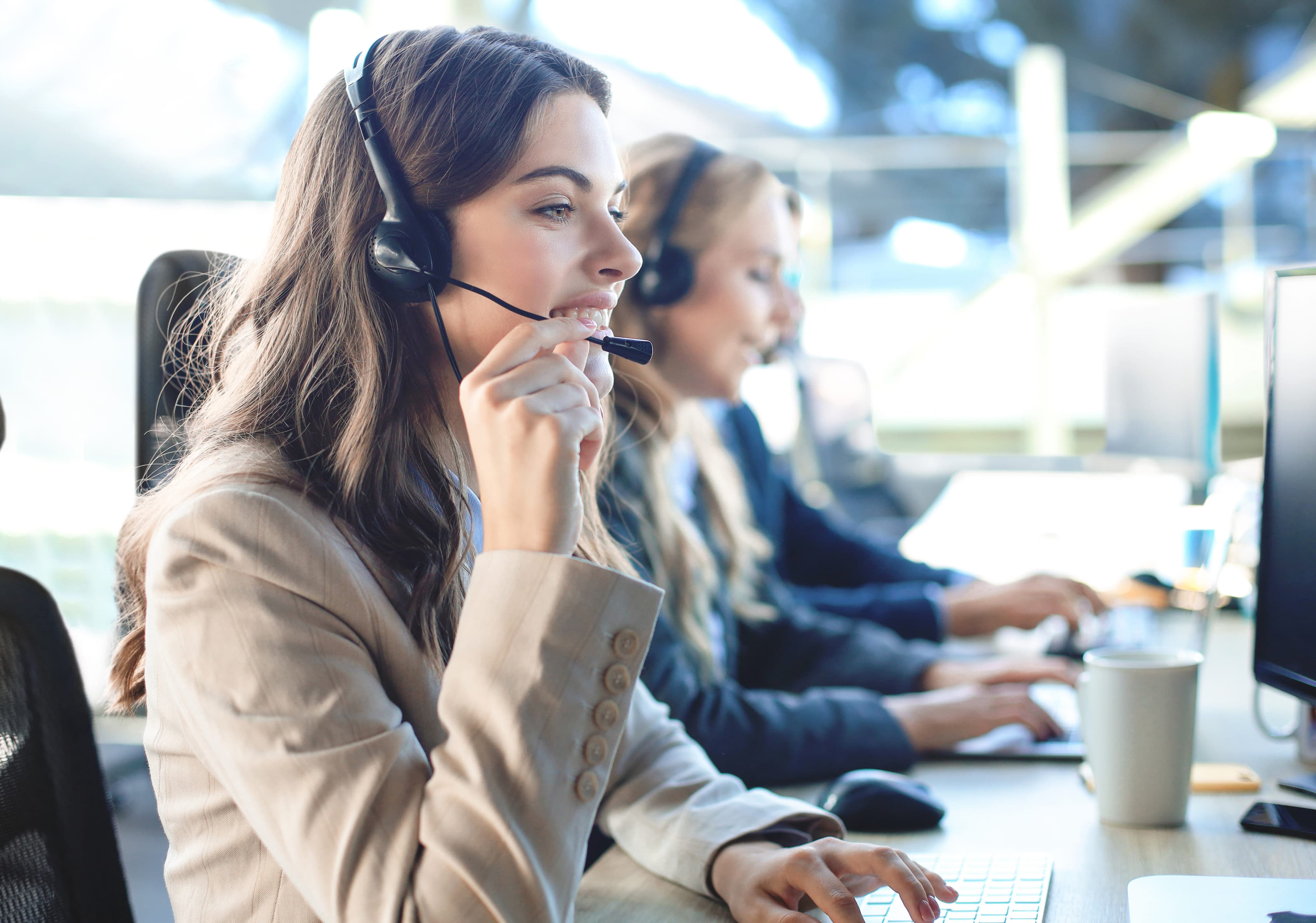 Female customer support operator smiling with colleagues in the background