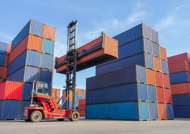 Forklift loading a container box onto a truck in a shipping yard