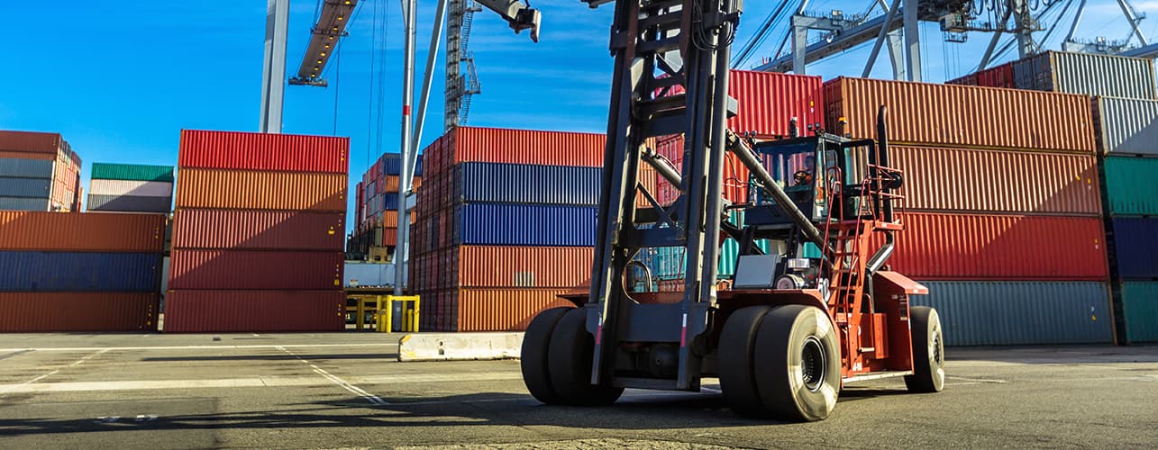 Forklift on the dock with containers in the background.