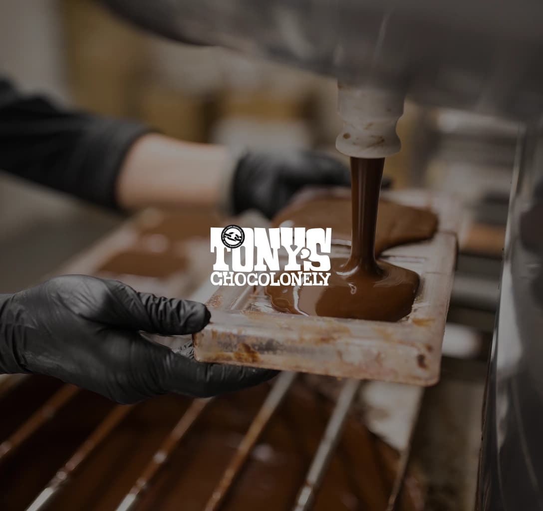 Tony’s Chocolonely logo featuring a person in the background making chocolate bars in a factory
